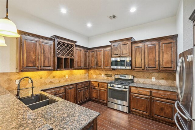 kitchen featuring decorative backsplash, a sink, stone countertops, stainless steel appliances, and recessed lighting