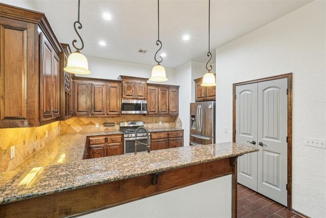 kitchen with decorative backsplash, stone counters, appliances with stainless steel finishes, and a peninsula