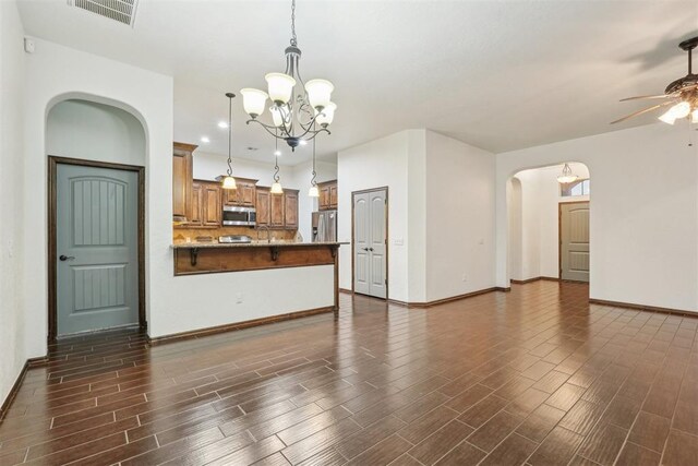 unfurnished living room featuring visible vents, baseboards, wood finish floors, arched walkways, and ceiling fan with notable chandelier