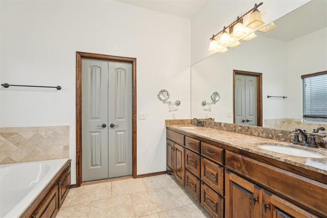 bathroom with double vanity, a sink, a garden tub, and a closet