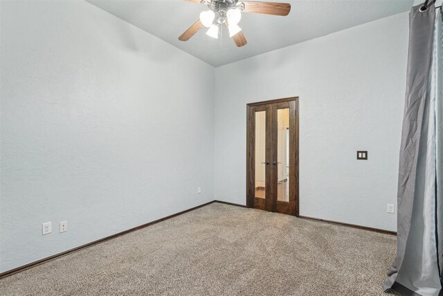 carpeted empty room with baseboards, ceiling fan, french doors, and lofted ceiling