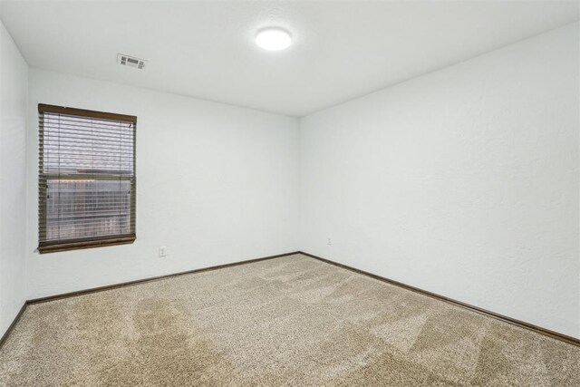 unfurnished room with carpet floors, baseboards, and visible vents