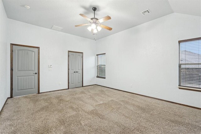 carpeted empty room with visible vents, a ceiling fan, baseboards, and vaulted ceiling
