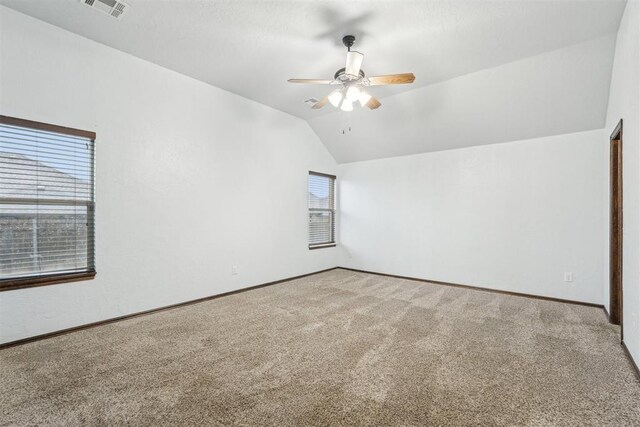 carpeted empty room featuring baseboards, ceiling fan, vaulted ceiling, and visible vents