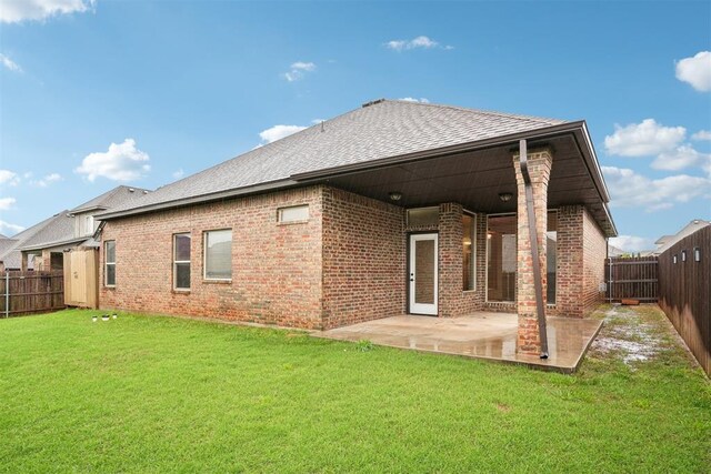 back of property with a patio, a fenced backyard, brick siding, a shingled roof, and a lawn