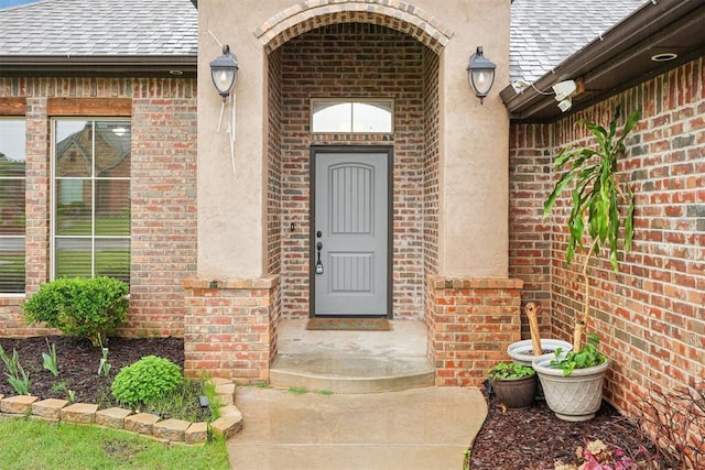 912 Lindsey Ln, Moore, OK 73160 - property entrance with roof with shingles, brick siding, and stucco siding