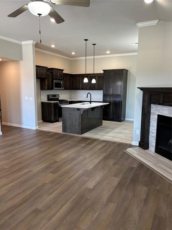 kitchen with baseboards, open floor plan, ceiling fan, tasteful backsplash, and stainless steel appliances