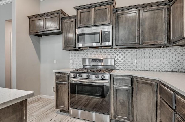 kitchen featuring dark brown cabinets, light stone countertops, appliances with stainless steel finishes, baseboards, and decorative backsplash