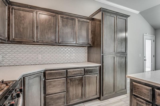 kitchen with crown molding, dark brown cabinetry, light countertops, backsplash, and range with gas cooktop