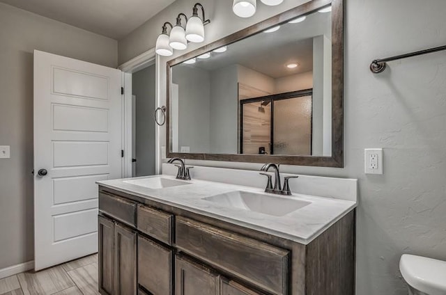 full bath featuring a sink, baseboards, a stall shower, and double vanity