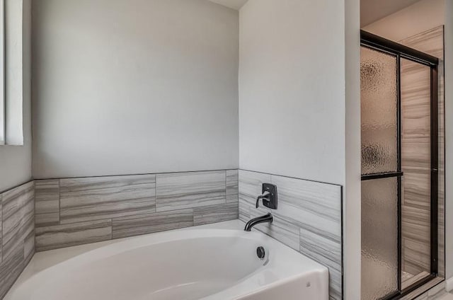 bathroom featuring a bath and a shower stall
