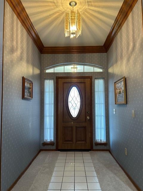 entryway with crown molding, light colored carpet, and a chandelier