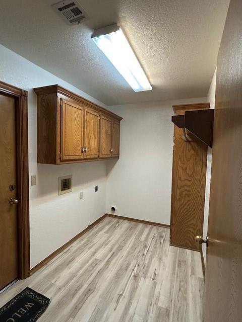 washroom featuring cabinet space, washer hookup, a textured ceiling, hookup for an electric dryer, and visible vents