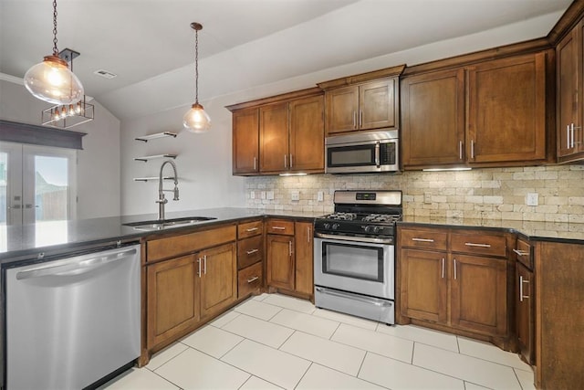 kitchen featuring appliances with stainless steel finishes, a sink, a peninsula, lofted ceiling, and backsplash