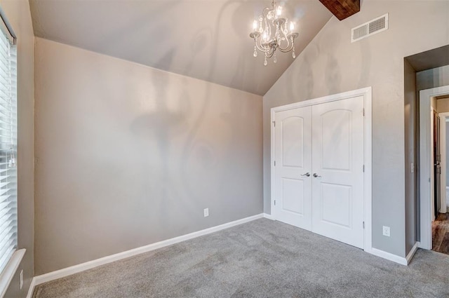 unfurnished bedroom with a chandelier, carpet, vaulted ceiling with beams, visible vents, and a closet