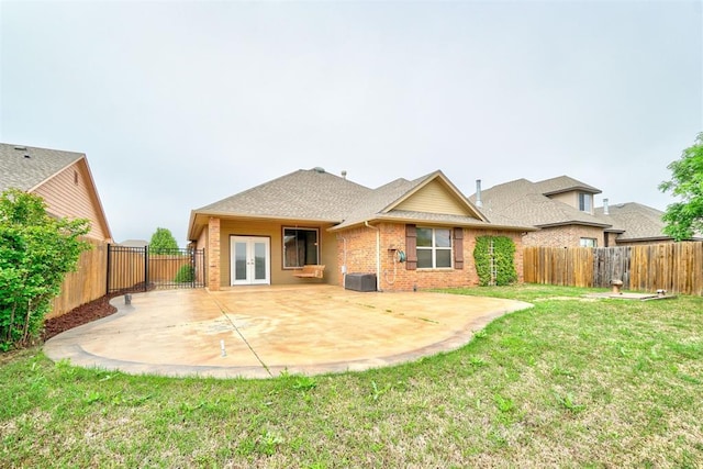 rear view of house with central AC, a fenced backyard, french doors, a patio, and a yard