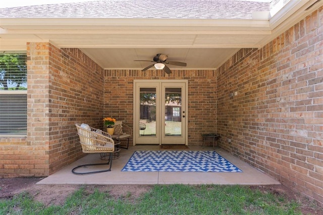 view of exterior entry featuring french doors, brick siding, a ceiling fan, a patio, and roof with shingles