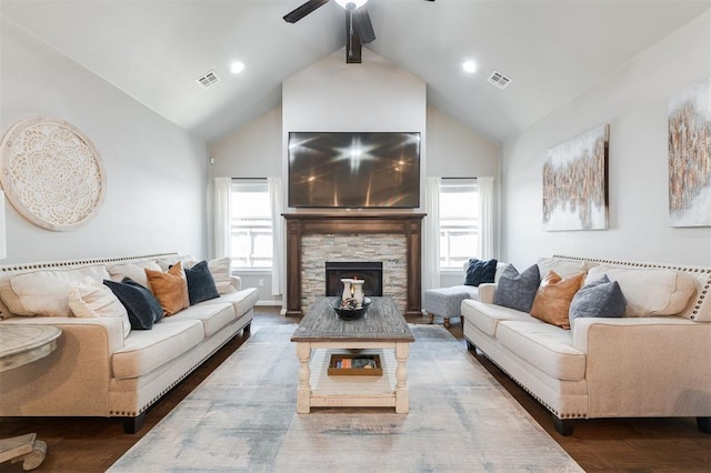 living area featuring high vaulted ceiling, a ceiling fan, wood finished floors, beam ceiling, and a stone fireplace