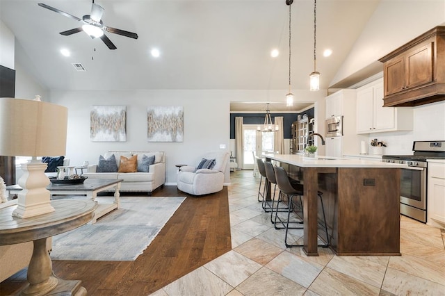 kitchen featuring stainless steel appliances, open floor plan, a sink, high vaulted ceiling, and a kitchen island with sink