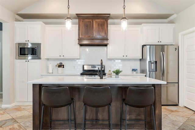 kitchen with appliances with stainless steel finishes, lofted ceiling, light countertops, an island with sink, and a sink