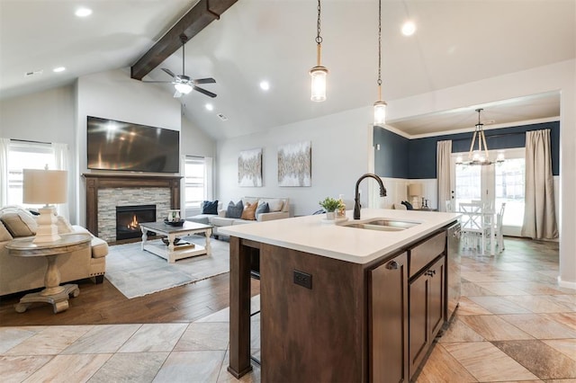 kitchen with a sink, beam ceiling, light countertops, ceiling fan, and pendant lighting