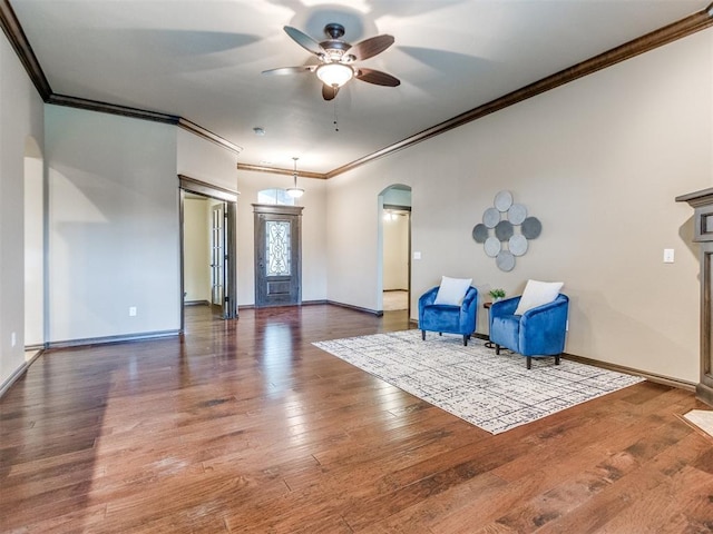 unfurnished room featuring wood-type flooring, arched walkways, a ceiling fan, baseboards, and ornamental molding