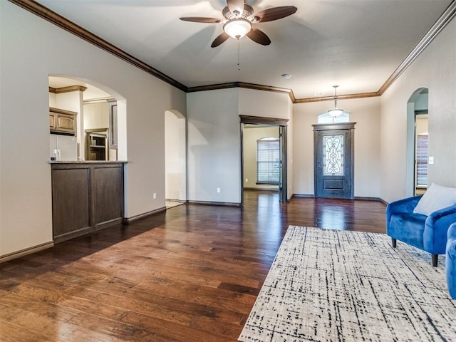 entryway with a ceiling fan, arched walkways, baseboards, ornamental molding, and dark wood-type flooring