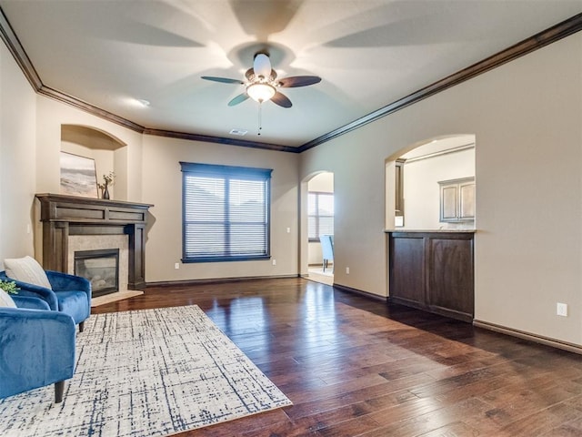 living area featuring ornamental molding, a fireplace, a ceiling fan, and hardwood / wood-style floors