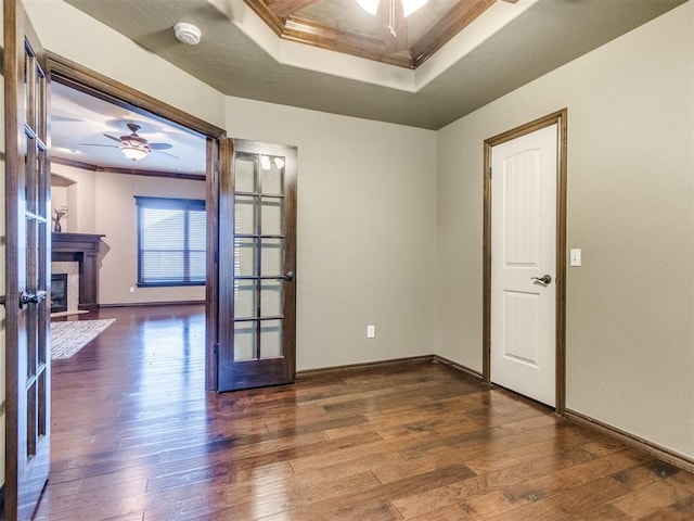 unfurnished room with wood-type flooring, a ceiling fan, a raised ceiling, and ornamental molding