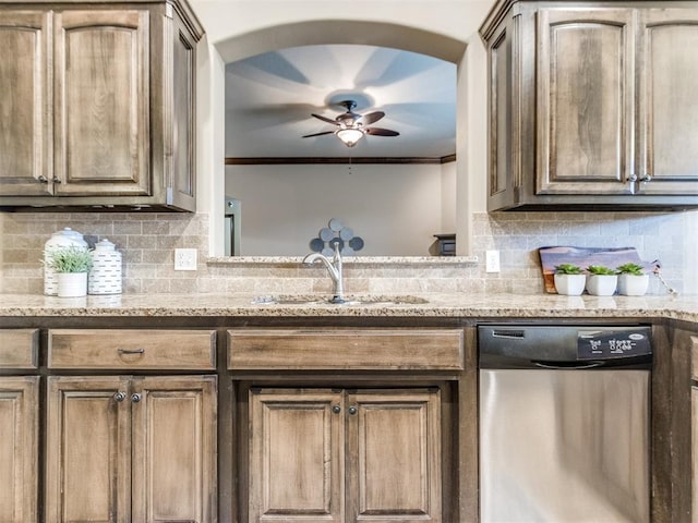 kitchen featuring stainless steel dishwasher, a ceiling fan, arched walkways, tasteful backsplash, and a sink