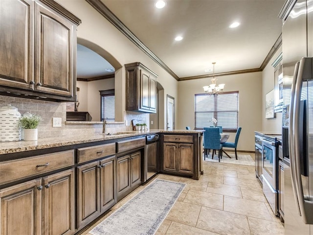 kitchen featuring arched walkways, a chandelier, stainless steel appliances, decorative backsplash, and ornamental molding