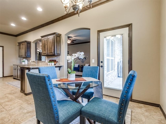 dining space featuring crown molding, arched walkways, baseboards, and recessed lighting