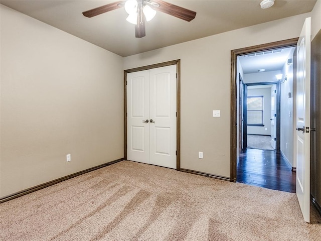 unfurnished bedroom featuring a closet, carpet flooring, baseboards, and a ceiling fan