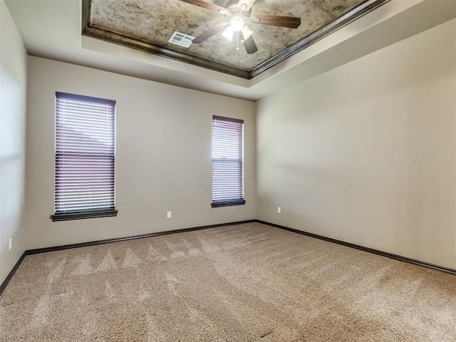 spare room featuring a tray ceiling, visible vents, ceiling fan, and carpet