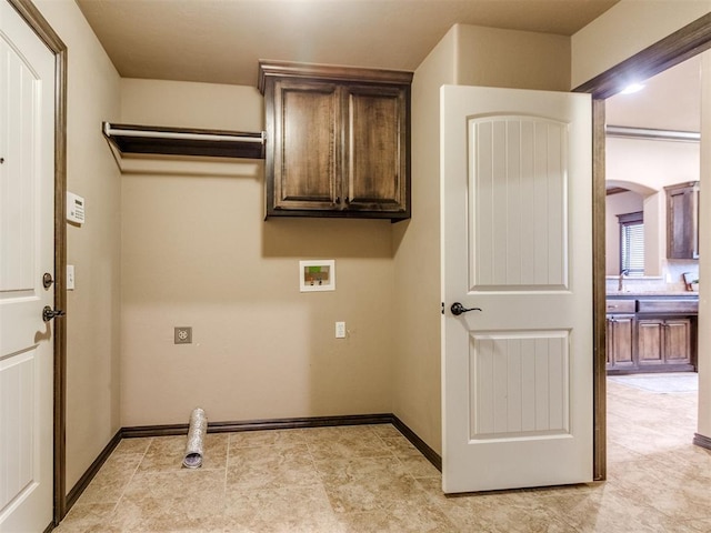 clothes washing area with baseboards, hookup for a washing machine, cabinet space, and arched walkways