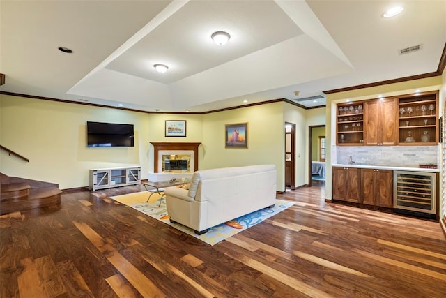 living room with wet bar, wood finished floors, a raised ceiling, wine cooler, and recessed lighting