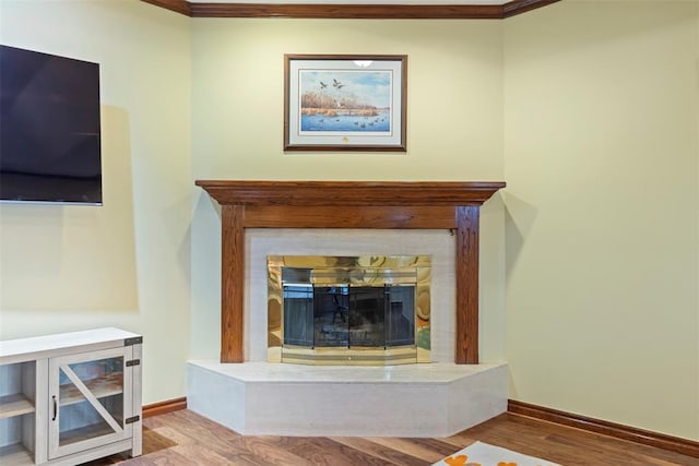 room details with crown molding, baseboards, a glass covered fireplace, and wood finished floors