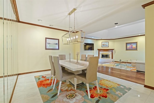 dining space with crown molding, tile patterned flooring, baseboards, a glass covered fireplace, and recessed lighting