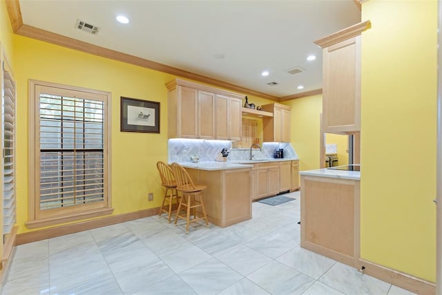 kitchen with visible vents, crown molding, light brown cabinetry, light countertops, and a peninsula