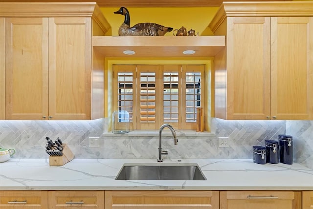 kitchen with a sink, light brown cabinetry, and backsplash