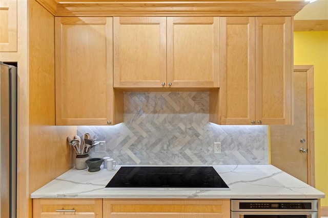 kitchen with appliances with stainless steel finishes, light brown cabinets, decorative backsplash, and light stone counters