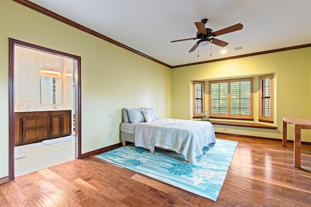 bedroom with visible vents, light wood-type flooring, baseboards, ornamental molding, and ensuite bath