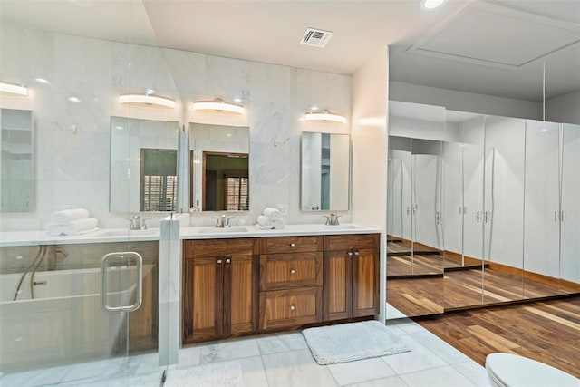 bathroom with a sink, toilet, double vanity, and visible vents