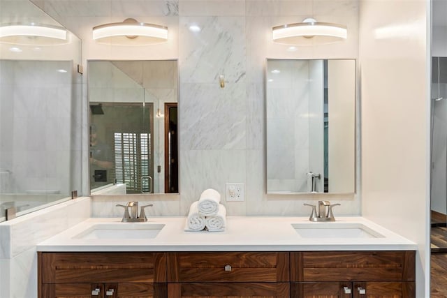 bathroom with a sink, a shower with shower door, and double vanity