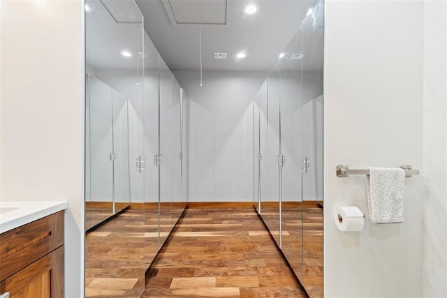 bathroom with recessed lighting, wood finished floors, and vanity