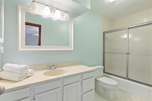 bathroom with vanity, tile patterned flooring, combined bath / shower with glass door, and toilet