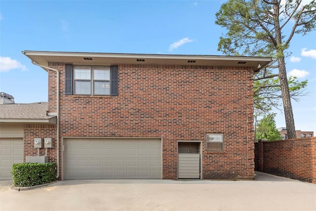 back of property featuring a garage, driveway, and brick siding
