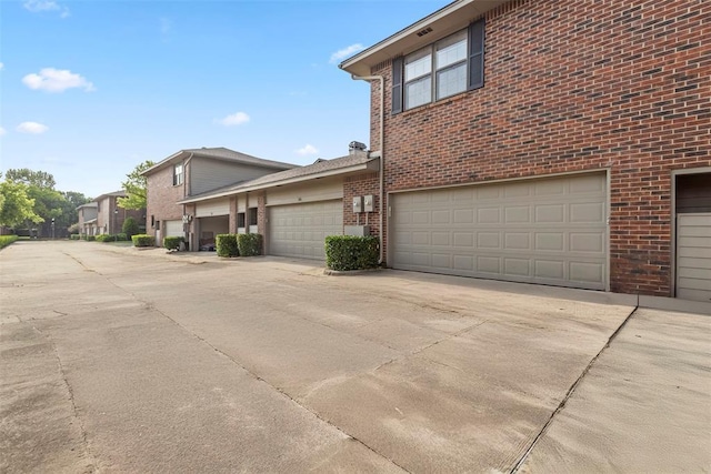 view of side of home with driveway and brick siding