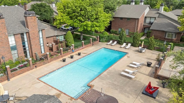 community pool with a patio area, fence, and a residential view