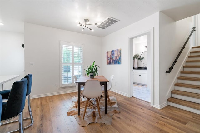 2517 NW 33rd St, Oklahoma City, OK 73112 - dining space featuring a notable chandelier, light wood-style floors, stairs, baseboards, and visible vents